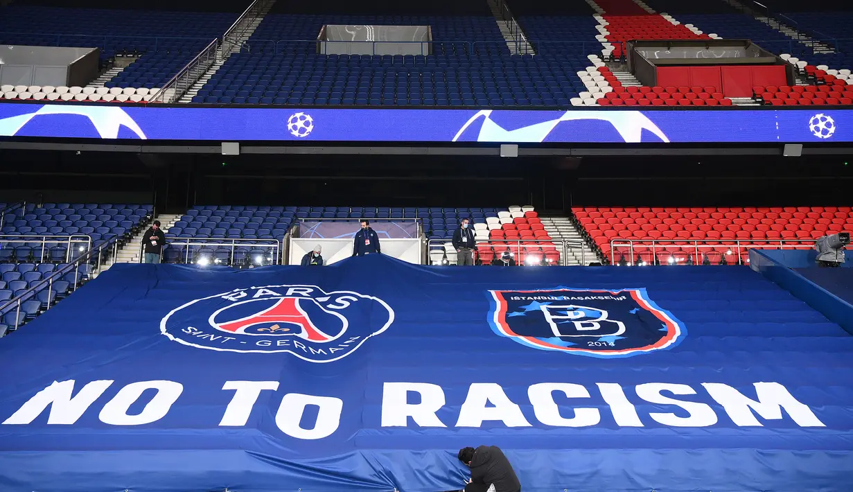 Petugas stadion memasang spanduk raksasa bertuliskan "NO TO RACISM" menjelang laga lanjutan Liga Champions Grup H antara PSG melawan Istanbul Basaksehir di Parc des Princes Stadium, Selasa (8/12/2020). (AFP/Franck Fife)