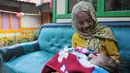 Nenek Anami terlihat menggendong seorang bayi di depan rumahnya di Purwakarta, Jabar, Minggu (17/5). Nenek yang diduga berusia 140 tahun ini akan mengikuti sayembara orang tertua di dunia dengan hadiah sekitar Rp13 miliar. (Liputan6.com/Herman Zakharia)