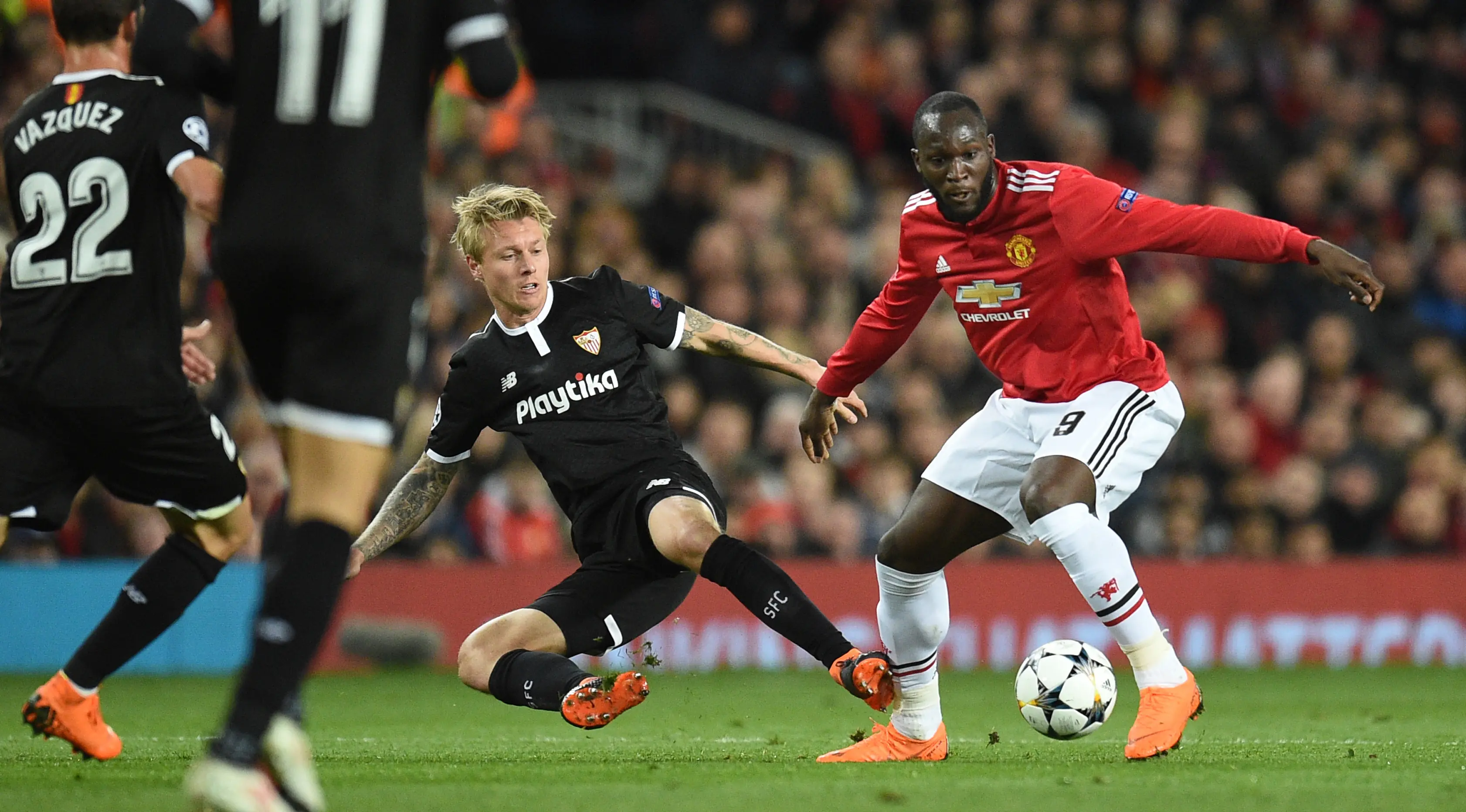 Bek Sevilla, Simon Kjaer berebut bola dengan striker Manchester United, Romelu Lukaku pada laga leg kedua 16 besar Liga Champions di Old Trafford, Selasa (13/3). Manchester United terhempas dari Liga Champions setelah kalah 1-2. (Oli SCARFF/AFP)