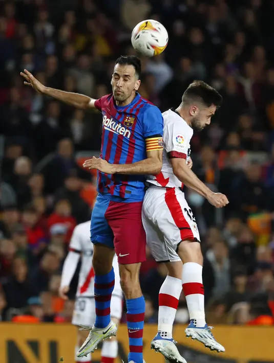 <p>Gelandang Barcelona, Sergio Busquets berebut bola dengan pemain Rayo Vallecano, Unai Lopez pada pertandingan lanjutan La Liga Spanyol di stadion Camp Nou di Barcelona, Spanyol, Senin (25/4/2022). Barcelona tumbang atas Rayo Vallecano 0-1. (AP Photo/Joan Monfort)</p>