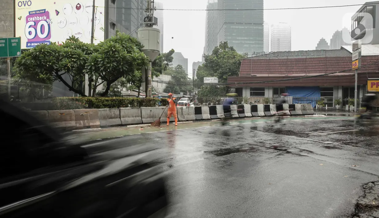 Petugas PPSU membersihkan sampah dekat beton pembatas di Jalan Senopati, Jakarta, Minggu (29/12/2019). Pascakejadian mobil tabrak Apotek Senopati, Suku Dinas Bina Marga memasangan beton pembatas untuk meminimalisir kejadian serupa terulang kembali. (Liputan6.com/Faizal Fanani)