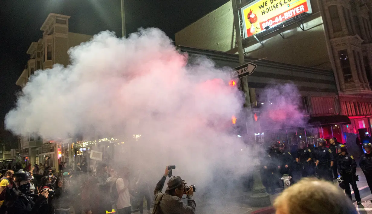 Fotogarfer mengambil gambar setelah polisi menyemprotkan gas air mata ke arah pengunjuk rasa di Oakland, California, Rabu (9/11). Unjuk rasa merebak di seluruh wilayah Amerika Serikat, menyusul kemenangan Donald Trump dalam Pilpres AS. (Josh Edelson/AFP)