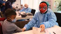 Petugas medis mengenakan topeng superhero mengecek kesehatan anak sebelum menyuntikkan vaksin Sinonvac kepada anak-anak saat mengikuti vaksinasi ke dua di Gedung  OJK, Jakarta, Minggu (16/01/2022). Sebanyak 350 anak karyawan OJK mengikuti vaksinasi Covid-19 dosis kedua. (Liputan6.com/Angga Yuniar)