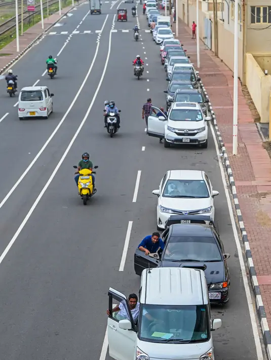 <p>Pengemudi mengantre di sepanjang jalan untuk membeli bahan bakar dari stasiun bahan bakar Lanka IOC di Kolombo, Selasa (24/5/2022). Sri Lanka yang kekurangan uang menaikkan harga bahan bakar secara tajam ke rekor tertinggi pada 24 Mei 2022, menyebabkan penderitaan lebih lanjut bagi 22 juta orang di negara itu dalam krisis terburuk sejak kemerdekaan. (Ishara S. KODIKARA / AFP)</p>