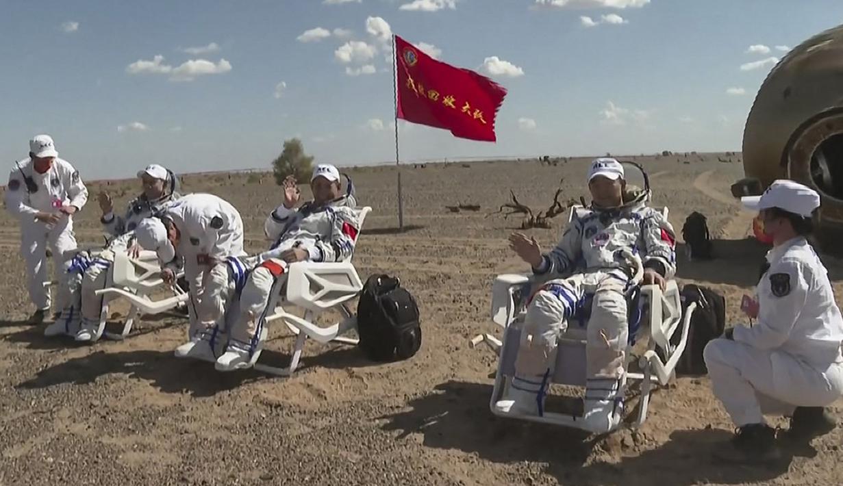 Astronot China Tang Hongbo (kiri), Nie Haisheng (tengah), dan Liu Boming (kanan) sedang diperiksa oleh petugas medis di luar kapsul pendaratan di Gurun Gobi, 17 September 2021. Trio astronot China kembali ke Bumi setelah misi luar angkasa. (CCTV/AFP)