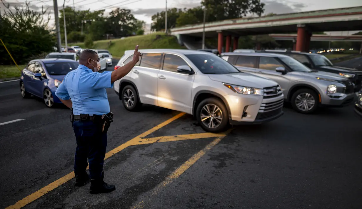 Petugas mengarahkan mobil di sepanjang R.H. Tood Avenue di sepanjang RH Tood Avenue setelah kecelakaan saat pemadaman listrik di San Juan, 7 April 2022. Lebih dari satu juta pelanggan di Puerto Rico tanpa listrik setelah kebakaran di pembangkit listrik utama. (AP Photo/Carlos Giusti)