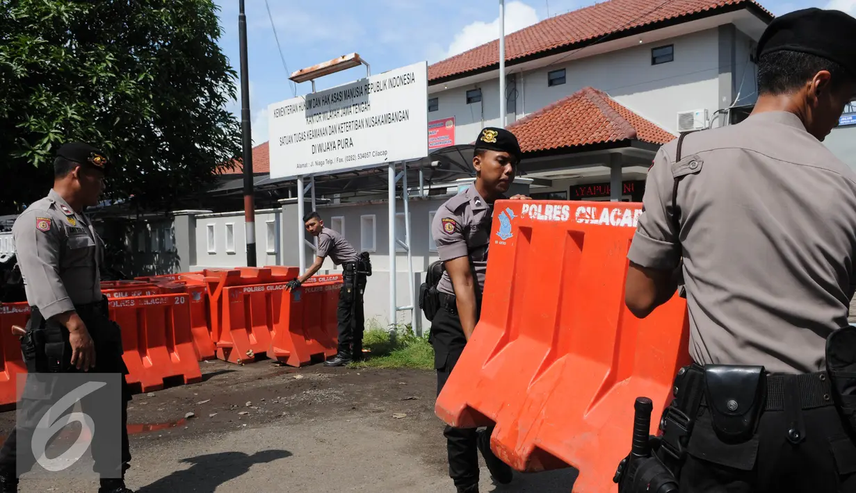 Polisi satuan Brimob mengangkat Water Barrier untuk barikade pengamanan menuju Dermaga Nusakambangan, Cilacap, Jawa Tengah, Rabu (27/7). Menjelang eksekusi Tahap 3 sejumlah persiapan dilakukan oleh Lapas Nusakambangan. (Liputan6.com/Helmi Afandi)