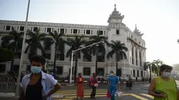 Orang-orang berjalan di sebelah Balai Kota Yangon di Yangon ketika militer menahan pemimpin de facto Myanmar Aung San Suu Kyi dan presiden Myint dalam kudeta, pada Senin (1/2/2021). Langkah itu terjadi beberapa hari setelah meningkatnya ketegangan antara pemerintah sipil dan militer yang berkuasa.