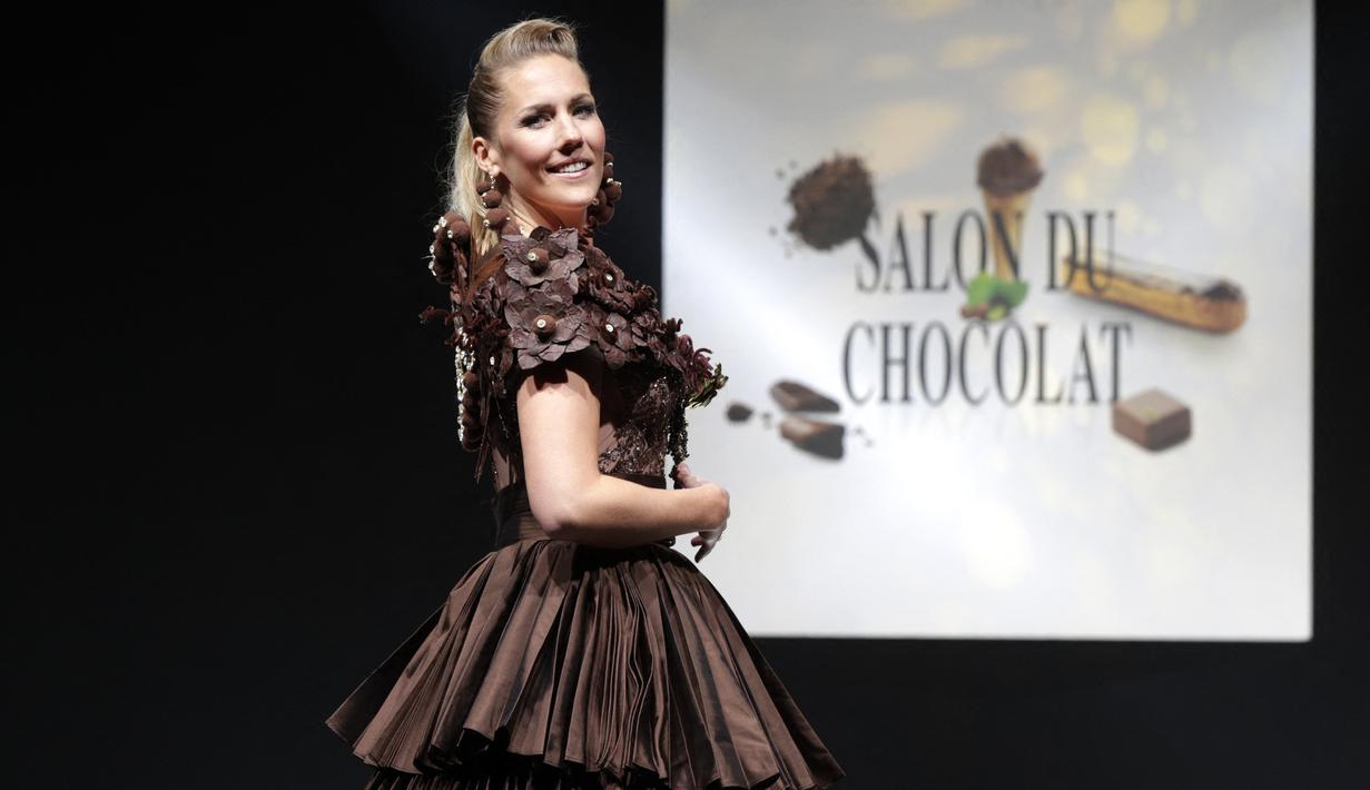 Wartawan Prancis-Inggris dan pembawa acara TV Sandy Heribert mengenakan kreasi yang dibuat dengan cokelat oleh koki pastry Hugues Pouget dan desainer Ricardo Davila selama Chocolate Fair (Salon du Chocolat) di Paris pada Rabu (27/10/2021). (GEOFFROY VAN DER HASSELT / AFP)