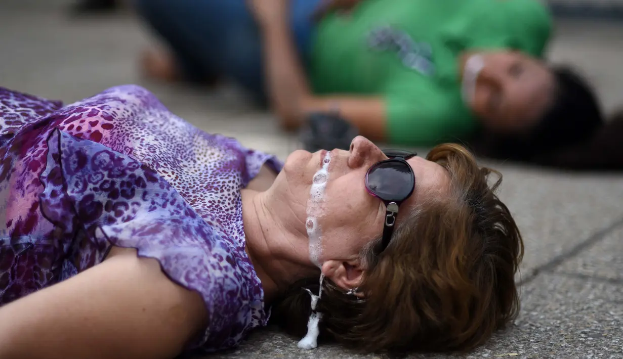 Dua orang demonstran tergeletak saat menggelar aksi di depan Kedubes AS di Mexico City, Minggu (9/4). Mereka mengecam serangan bom kimia yang telah menewaskan warga Suriah dan menolak intervensi AS. (AFP PHOTO / Pedro Pardo)