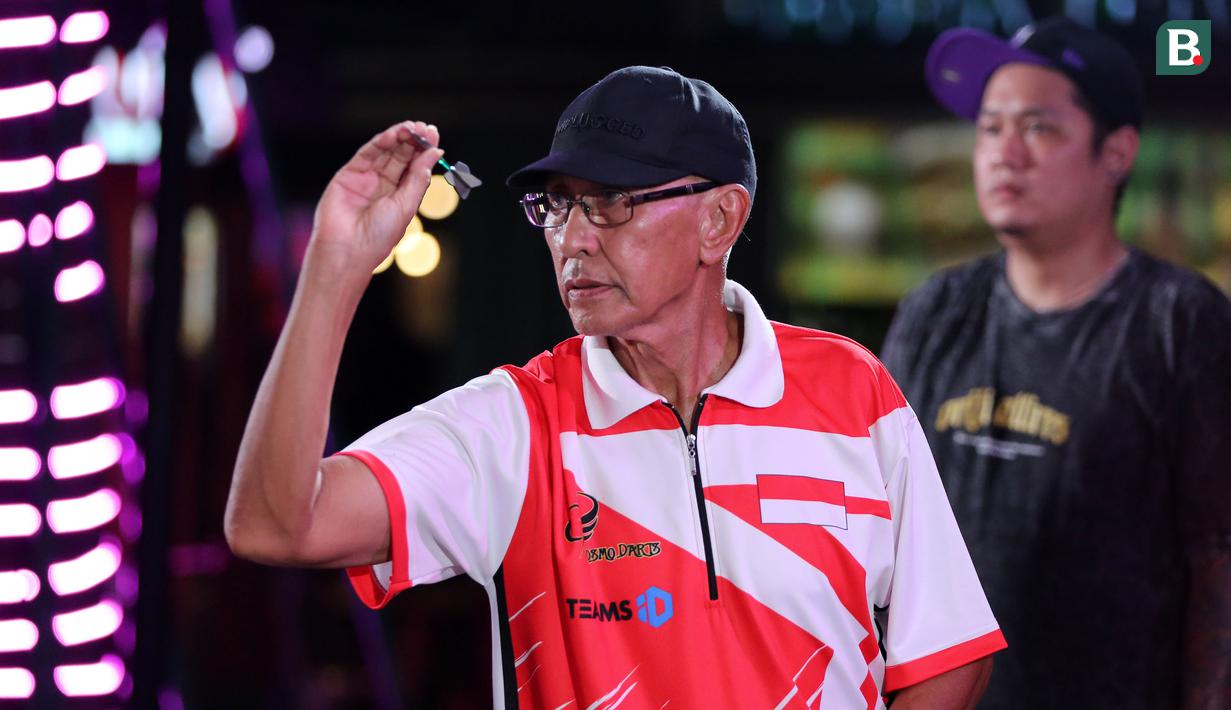Pemain Darts, Haji Suwendi saat berkompetisi dalam turnamen Darts National Competition series 2 yang berlangsung di Sedayu City, Jakarta, Minggu (28/04/2024). Haji Suwendi kalah dari Tirta Suparjo dengan skor 1-3. (Bola.com/Revi Muzaki)