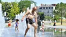Seorang pria menyegarkan dirinya di air mancur sambil menikmati matahari musim panas di Nantes, Prancis barat, Senin (19/6). Suhu temperatur di Prancis mencapai 36 derajat celcius. (AFP Photo / LOIC VENANCE)