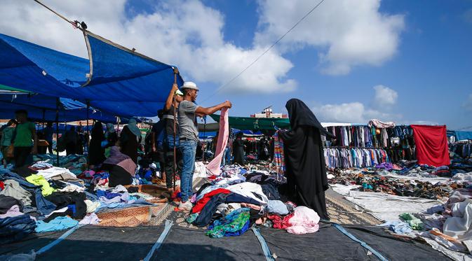Seorang wanita Palestina berbelanja pakaian di sebuah pasar tradisional yang kembali dibuka setelah pelonggaran karantina wilayah di kamp pengungsi Nuseirat di Jalur Gaza tengah, Senin (13/7/2020). (AFP/Mohammed Abed)