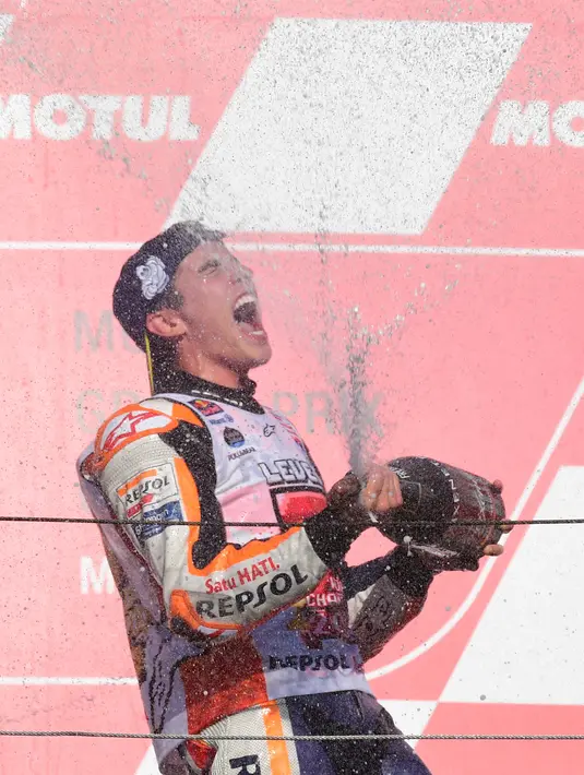Pembalap Repsol Honda, Marc Marquez menyemprotkan sampanye saat berselebrasi di atas podium setelah memenangi balapan MotoGP Jepang 2018 di Twin Ring Motegi, Minggu (21/10). Marquez menang dengan catatan waktu 42 menit 36,438 detik . (Martin BUREAU / AFP)