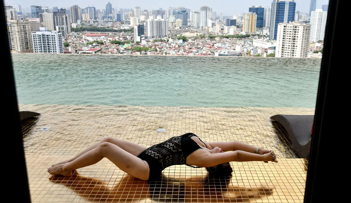 Seorang tamu berpose di kolam tanpa yang ada di hotel Dolce Hanoi Golden Lake yang baru saja diresmikan di Hanoi, Vietnam pada Kamis (2/7/2020). Hotel tersebut merupakan hotel berlapiskan emas 24 karat pertama di dunia. (Manan VATSYAYANA / AFP)
