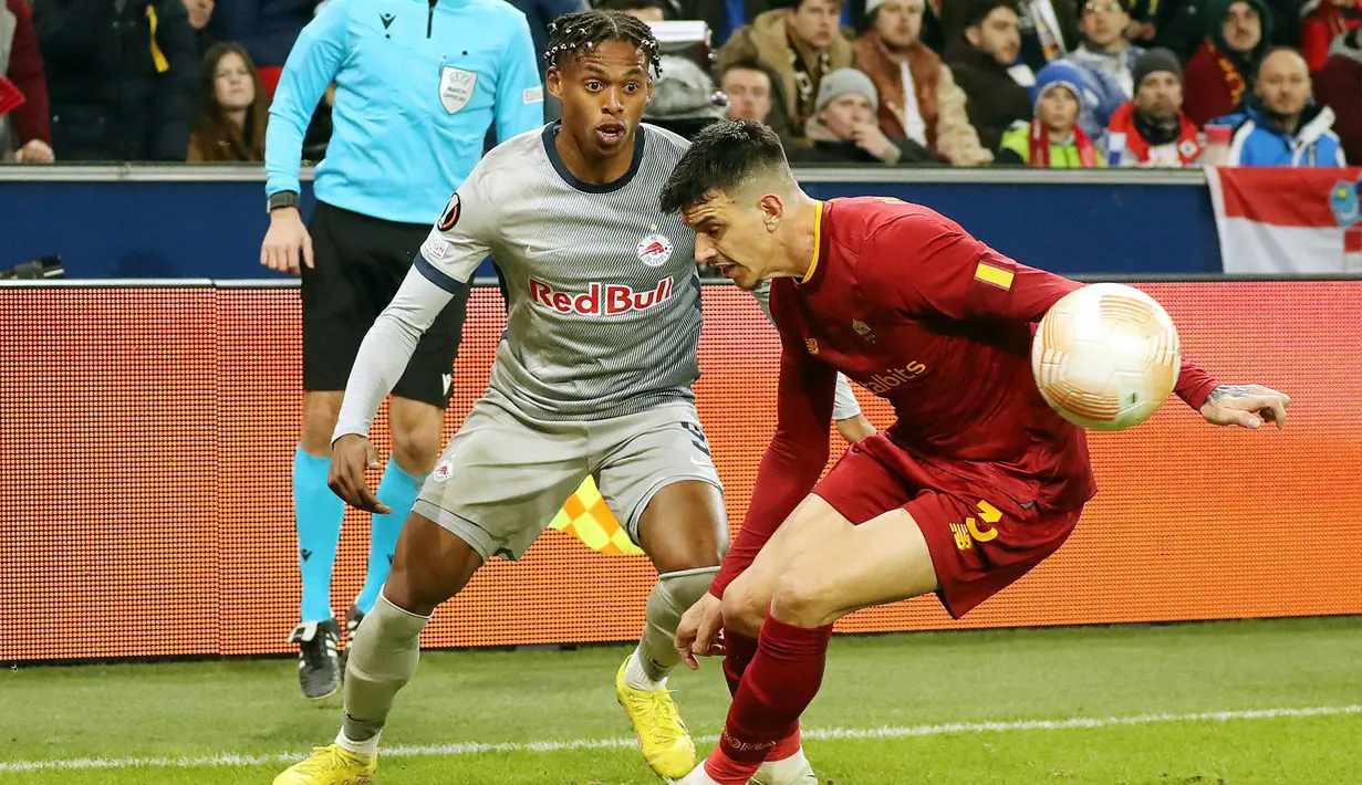 Bek AS Roma Roger Ibanez da Silva (kanan) berebut bola dengan penyerang RB Salzburg Chukwubuike Junior Adamu pada leg pertama playoff babak 16 besar Liga Europa di Red Bull Arena, Salzburg, Jumat (17/2/2023) dini hari WIB. Roma memberikan perlawanan sepadan, tapi bermasalah dalam ritme dan penyelesaian akhir. (KRUGFOTO / APA / AFP)