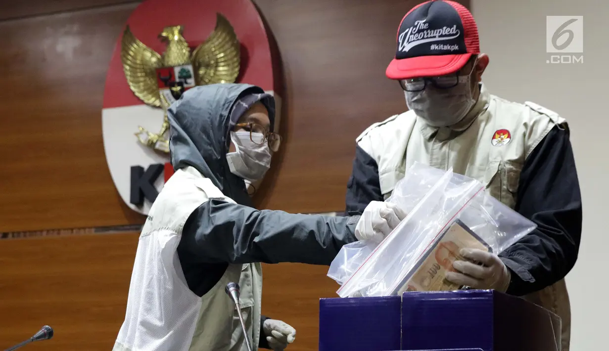 Petugas KPK merapikan barang bukti uang hasil OTT di Gedung KPK, Jakarta, Sabtu (26/6/2019). Dalam OTT tersebut, KPK menyita uang 20.874 dolar Singapura, 700 USD dan Rp 200 juta dari lima tersangka. (Liputan6.com/Helmi Fithriansyah)