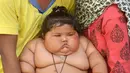 Chahat, bayi berusia 8 bulan, didampingi orangtuanya di rumah mereka di Amritsar, India, Senin (17/4). Tidak diketahui pasti kenapa berat badan Chahat mengalami kenaikan yang drastis dan nafsu makannya tak bisa ditekan dengan baik. (NARINDER NANU/AFP)