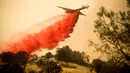 Pemadam kebakaran menggunakan pesawat membuang fire retardant untuk mengatasi kebakaran di Mariposa, California (19/7). Kebakaran ini telah melahap lebih dari 45.000 hektar lahan. (AFP Photo/Josh Edelson)