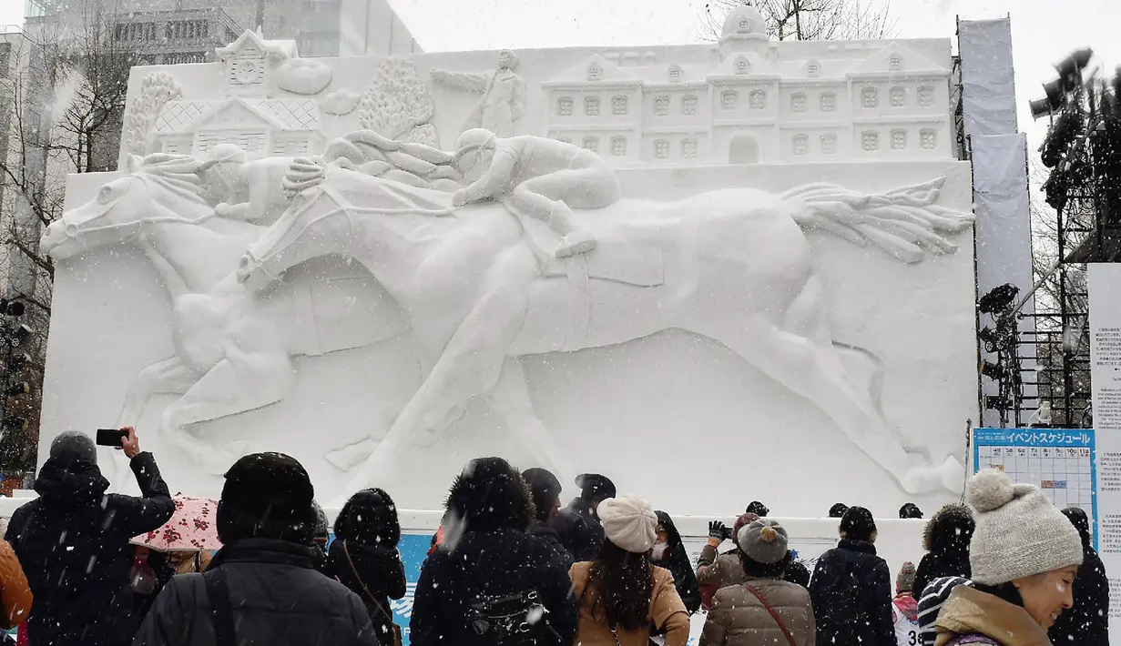 Sejumlah pengunjung melihat patung es balap kuda selama hari pembukaan Festival Salju Sapporo di Sapporo, Jepang (4/2). Festival salju Sapporo pertama kali diselengarakan tahun 1950. (AFP Photo/Jiji Press)