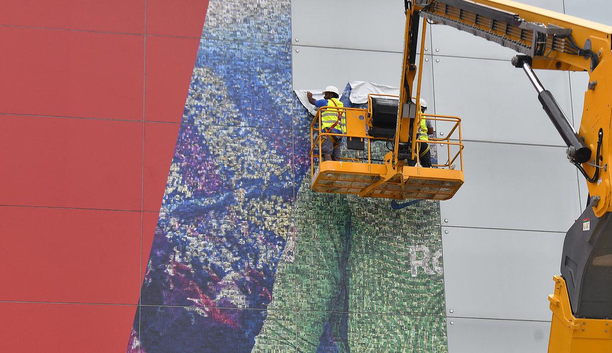 Pekerja melepas poster yang menampilkan pemain depan Argentina, Lionel Messi di pintu masuk Stadion Camp Nou, Barcelona pada Selasa, 10 Agustus 2021. Lionel Messi resmi meninggalkan Barcelona akibat masalah finansial klub dan peraturan dari Liga Spanyol. (AFP/Pau Barrena)