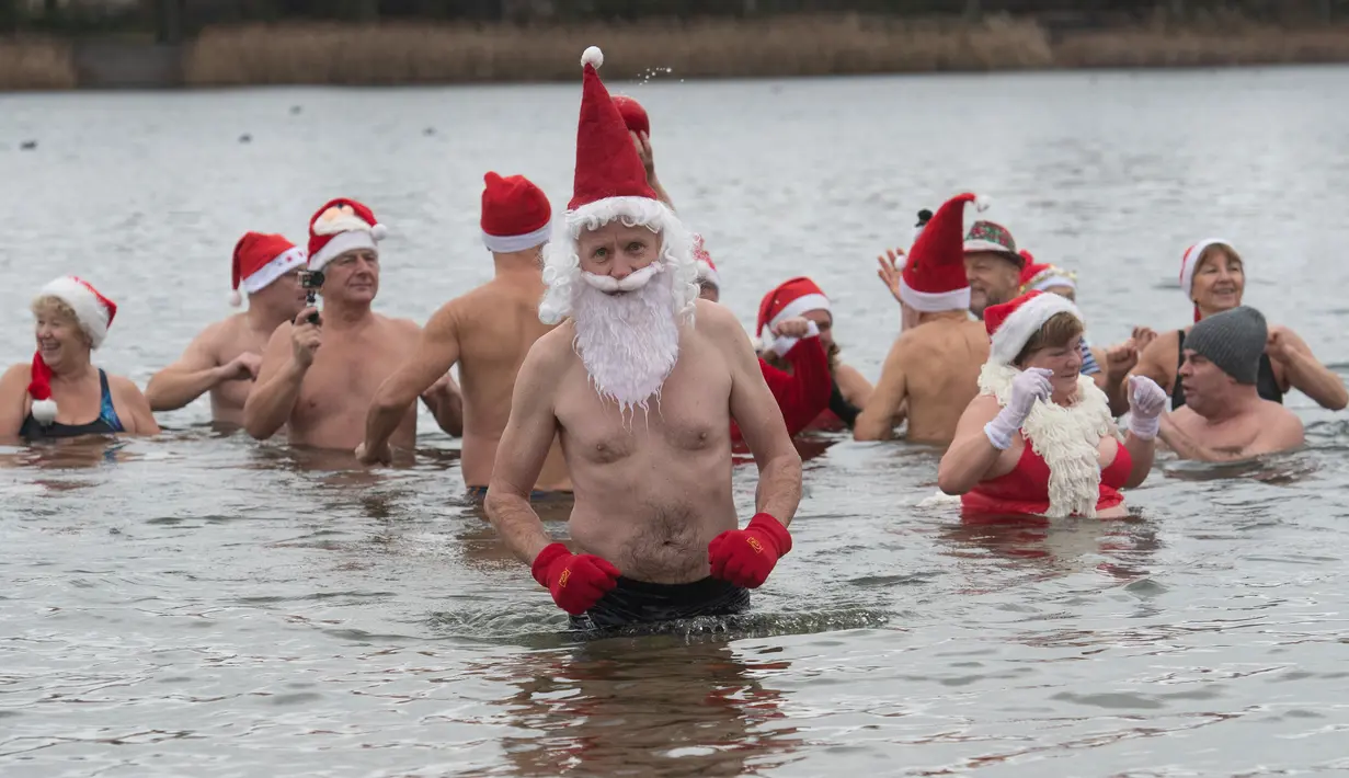 Anggota klub renang "Berliner Seehunde" (Berlin Seals) berendam di Danau Orankesee, Berlin, Minggu (25/12). Kegiatan yang sudah menjadi tradisi ini merupakan bagian dari perayaan tradisional Natal bagi warga Berlin. (Paul Zinken/dpa via AP)