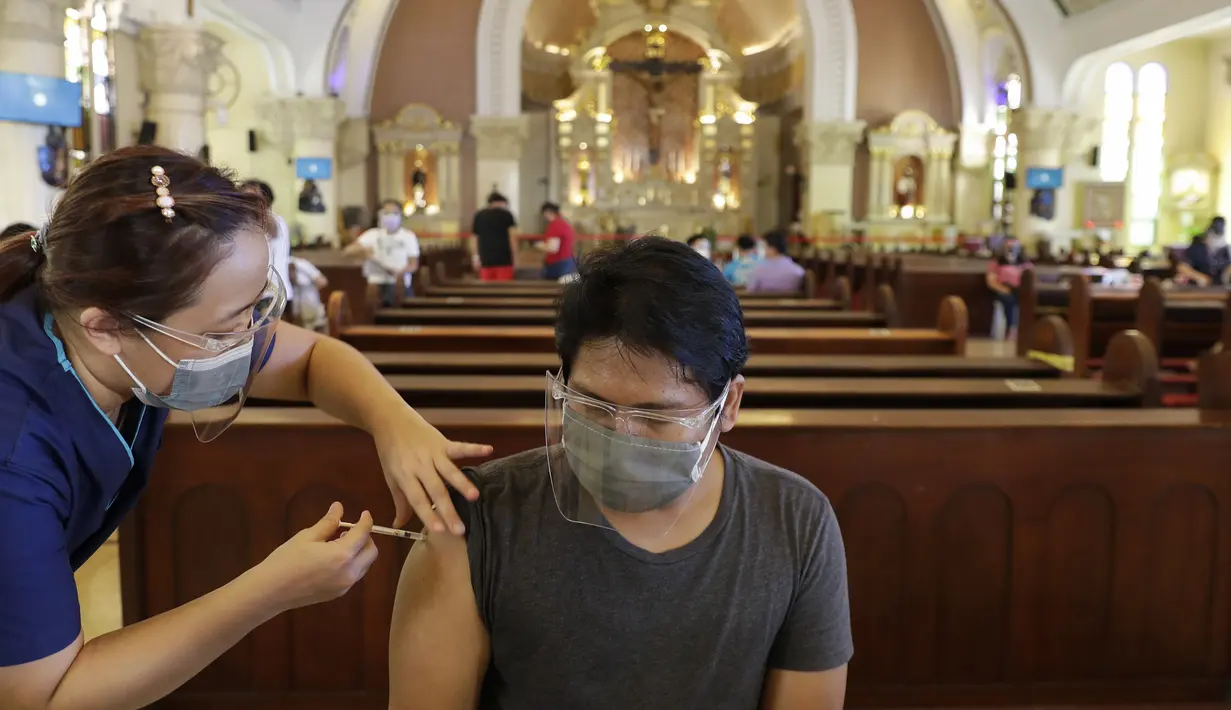 Petugas kesehatan menyuntik seorang pria dengan vaksin COVID-19 AstraZeneca di dalam gereja Paroki Hati Kudus Yesus di Quezon City, Filipina, Senin (17/5/2021). Sempat ditangguhkan, Filipina melanjutkan penggunaan vaksin AstraZeneca pada penduduk berumur di bawah 60 tahun. (AP Photo/Aaron Favila)
