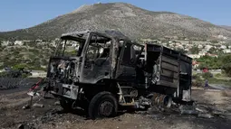 Sebuah mobil pemadam kebakaran hangus dalam kebakaran lahan yang melanda dekat Kalyvia, Yunani, Kamis (3/8). Puluhan petugas dan mobil pemadam kebakaran dikerahkan dalam operasi pemadaman kebakaran besar tersebut. (AP/Thanassis Stavrakis)