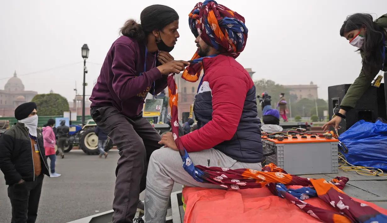 Seorang pria mengikat sorban seorang seniman saat mereka berlatih untuk parade Hari Republik mendatang, di New Delhi, India (17/1/2022). Parade akan ditandai dengan pawai oleh berbagai cabang militer serta tampilan senjata dan rudal. (AP Photo/Manish Swarup)