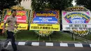 Pekerja melintas di depan karangan bunga ucapan selamat dilantiknya Komjen Pol Tito Karnavian di Mabes Polri, Jakarta, Rabu (13/7). Tito Karnavian akan dilantik menjadi Kapolri di Istana Negara oleh Presiden Jokowi. (Liputan6.com/Helmi Fithriansyah)