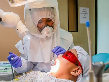 Dr. Maureen P. Ines-Manzano, seorang dokter gigi, memeriksa pasiennya di dalam kliniknya di Manila, Filipina, pada 19 Oktober 2020. Pasien Dr. Manzano menjulukinya "dokter gigi astronaut" karena mengenakan setelan PAPR untuk melindungi pasien dan dirinya dari COVID-19. (Xinhua/Rouelle Umali)