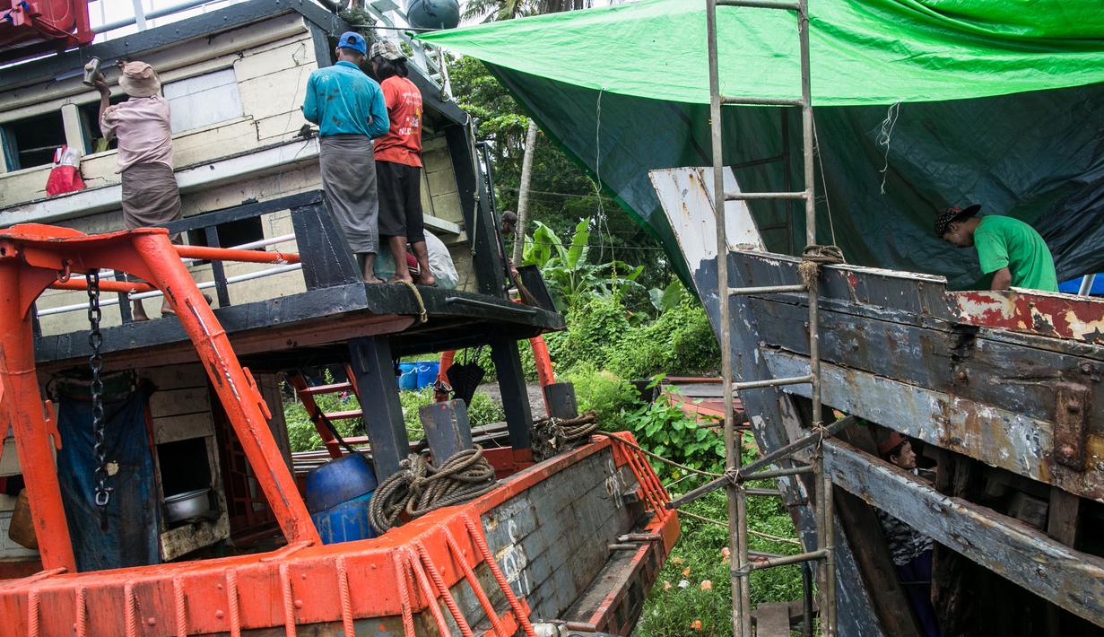 Para pekerja saat memperbaiki sebuah kapal di galangan kapal di tepi Sungai Yangon, yang terletak di pinggiran Yangon, Myanmar (30/7/2019). (AFP Phot/Sai Aung Main)