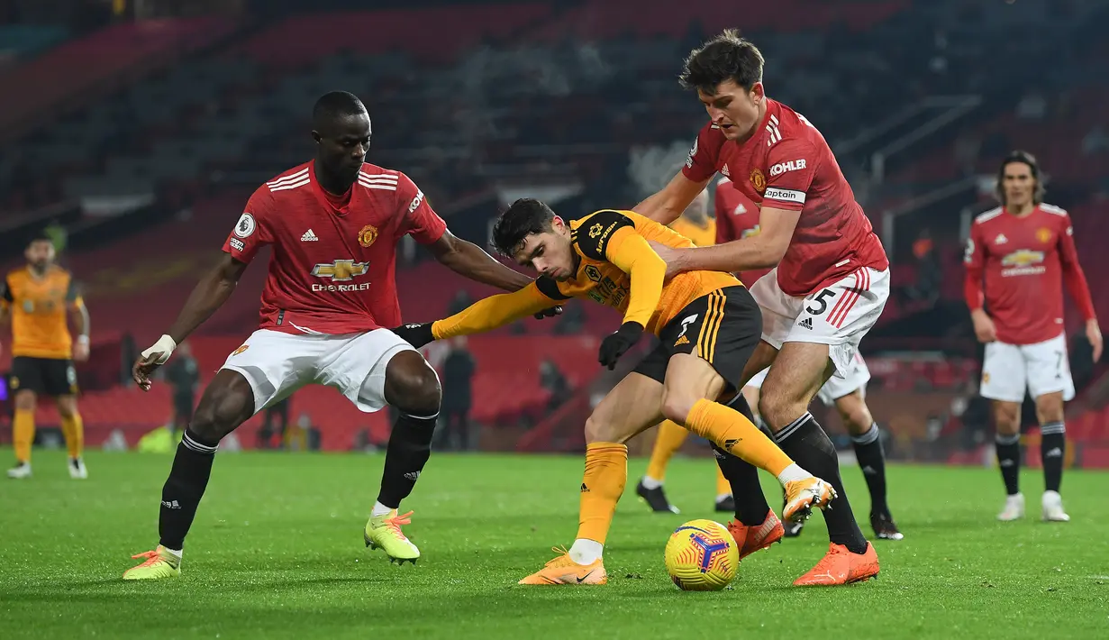 Gelandang Wolverhampton Wanderers, Pedro Neto (tengah) dikurung dua bek Manchester United, Eric Bailly (kiri) dan Harry Maguirre dalam laga lanjutan Liga Inggris 2020/21 pekan ke-16 di Old Trafford, Selasa (29/12/2020). Wolverhampton kalah 0-1 dari Manchester United. (AFP/Michael Regan/Pool)