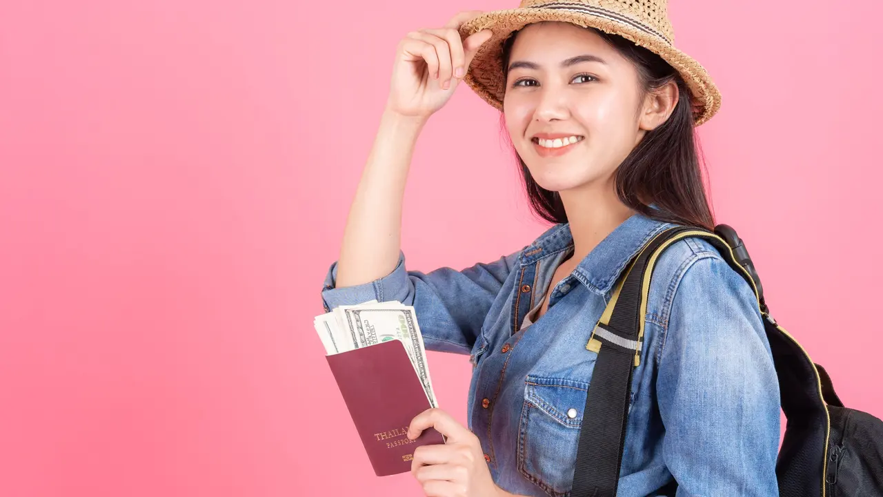 Seorang perempuan mengenakan pakaian berlibur dan memegang paspor (Foto Dok: Freepik/jcomp)