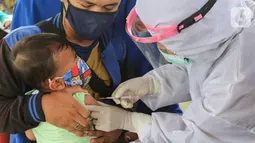 Bidan lengkap dengan baju APD memberi imunisasi pada anak di Posko Imunisasi, Kelurahan Bakti Jaya, Tangerang Selatan, Senin (11/5/2020). Bila melewatkan imunisasi, anak dikhawatirkan rentan tertular penyakit dan mengalami sakit berat saat pandemi Covid-19. (Liputan6.com/Fery Pradolo)
