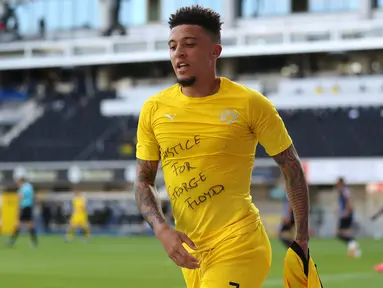 Gelandang Borrusia Dortmund, Jadon Sancho berselebrasi menunjukkan tulisan di kaos dalam 'Justice for George Floyd' usai mencetak gol ke gawang SC Paderborn 07 di Benteler Arena di Paderborn, Jerman (1/6/2020). Dalam pertandingan ini Dortmund menang telak 6-1 atas Paderborn. (Lars Baron/Pool via AP)