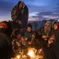 Sebuah keluarga menghangatkan diri di luar kantor Direktorat Bencana tempat mereka berkemah, di Herat, Afghanistan (29/11/2021). Sekitar 2000 pengungsi meninggalkan desa Allahyar di provinsi Ghor karena kekeringan dan mencari bantuan dari pemerintah daerah di Herat. (AP Photo/Petros Giannakouris)