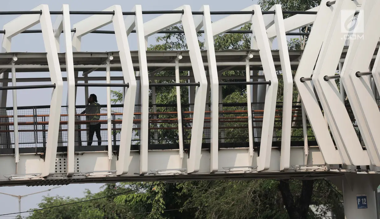 Pekerja menyelesaikan pembangun jembatan Skybridge di Ramangun, Jakarta, Kamis (4/7/2019). Pembangunan Skybridge sudah 98 persen rampung, yang nantinya akan menghubungkan Stasiun Kereta LRT Velodrome dengan halte busway Pemuda Rawamangun akan rampung akhir bulan ini. (Liputan6.com/Faizal Fanani)