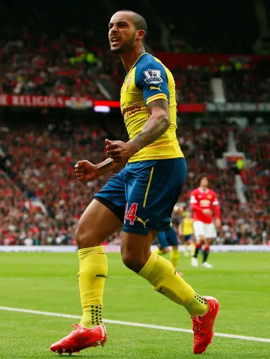 Gelandang Arsenal, Theo Walcott melakukan selebrasi usai pemain MU, Tyler Blackett melakukan gol bunuh diri di Laga Liga Premier Inggris di Old Trafford, Minggu (17/5/2015). Manchester United bermain imbang 1-1 atas Arsenal. (Reuters/Jason Cairnduff)