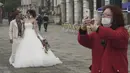 Pasangan yang baru menikah berpose di Venesia, Italia, Selasa (25/2/2020).Pemerintah Italia akan melarang orang berhenti berciuman di depan umum, menghindari berjabatan tangan dan menjaga jarak yang aman dari masing-masing lain untuk membatasi penyebaran virus corona.  (AP Photo/Renata Brito)