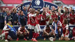 Striker Arsenal, Pierre-Emerick Aubameyang (tengah) menjatuhkan trofi saat merayakan gelar juara Piala FA usai mengalahkan Chelsea pada pertandingan final Piala FA di stadion Wembley, Minggu (2/8/2020).  Aubameyang terlihat kaget sambil memegang kepalanya saat trofi terjatuh. (Adam Davy/Pool via AP)
