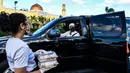 Seorang wanita menerima paket makanan buka puasa Ramadhan dari seorang sukarelawan Asosiasi Komunitas Muslim Miami dan Yayasan Lumba-Lumba Miami di Miami Gardens, Florida, Amerika Serikat, Selasa (27/4/2021). Distribusi makanan dilakukan secara drive thru. (CHANDAN KHANNA/AFP)