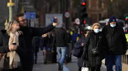 Orang-orang berjalan melintasi Jembatan Westminster di London, Kamis (9/12/2021). Perdana Menteri Inggris Boris Johnson kembali mendesak orang untuk bekerja dari rumah dan kewajiban menunjukkan sertifikat vaksin untuk memasuki klub malam dan tempat dengan kerumunan besar. (AP Photo/Frank Augstein)