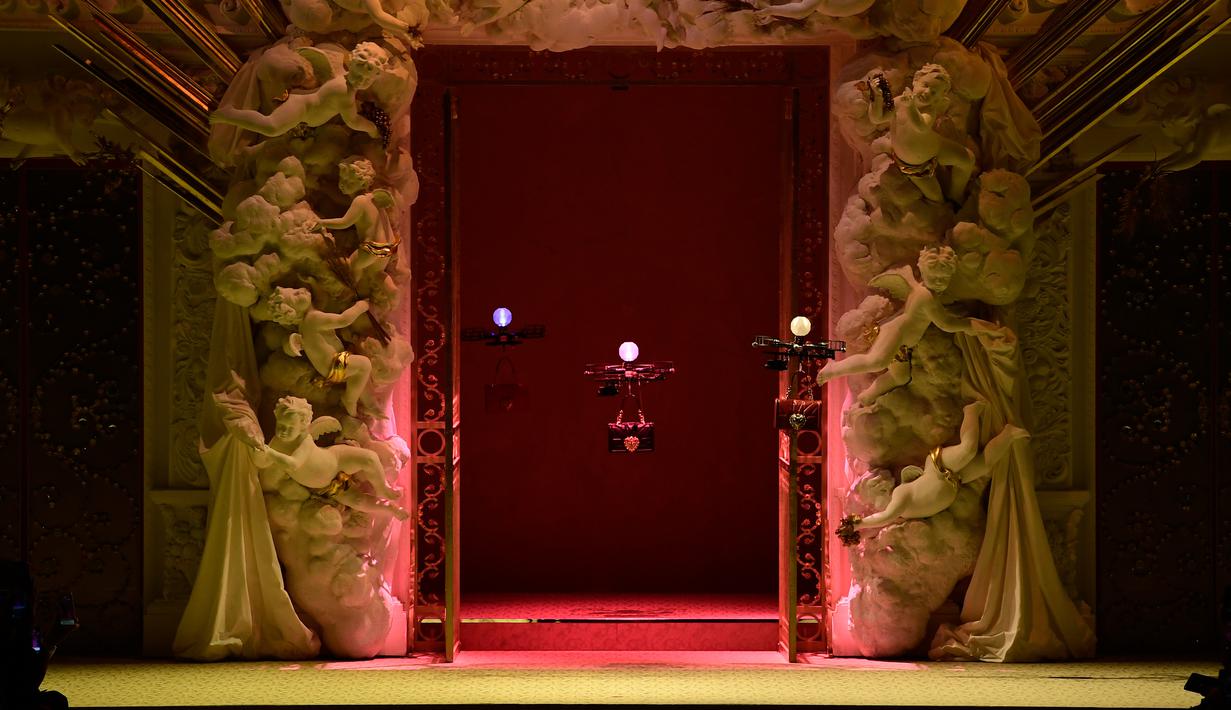Pesawat tanpa awak (drone) keluar dari belakang panggung sembari terbang membawa koleksi tas musim gugur Dolce & Gabbana pada Milan Fashion Week 2018, Minggu (25/). Aksi yang tak biasa ini membuat para tamu terkejut. (Miguel MEDINA/AFP)
