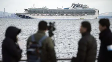 Seorang kru TV memfilmkan sebuah kapal pesiar Diamond Princess berlabuh di Pelabuhan Yokohama di Yokohama, Tokyo (4/2/2020). Otoritas Kesehatan Jepang mengkarantina 3.700 orang di dalam sebuah kapal pesiar setelah satu penumpang dinyatakan positif terkena virus corona.  (AP Photo/Eugene Hoshiko)