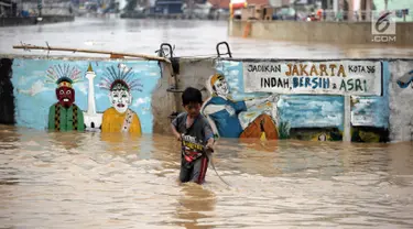 Seorang anak bermain air saat banjir menggenangi Jalan Jatinegara Barat, Jakarta Timur, Selasa (6/2). Deras dan tingginya debit air di Kali Ciliwung membuat Jalan Jatinegara Barat terputus. (Liputan6.com/Arya Manggala)