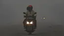 Pengendara motor menerobos jalan berkabut asap di jalan dekat pelabuhan Tanjung Siapi Api, Palembang, Sabtu (19/9/2015). Kabut asap akibat kebakaran hutan ini sangat membahayakan kesehatan dan keselamatan. (Reuters/Beawiharta)