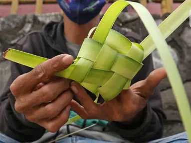 Pedagang menyelesaikan pembuatan kulit ketupat di kawasan Cibubur, Jakarta, Rabu (30/7/2020). Pedagang musiman menjelang Idul Adha tersebut menjual kulit ketupat dengan harga Rp 10 ribu, sedangkan ketupat yang siap untuk dihidangkan seharga Rp 30 ribu. (Liputan6.com/Herman Zakharia)