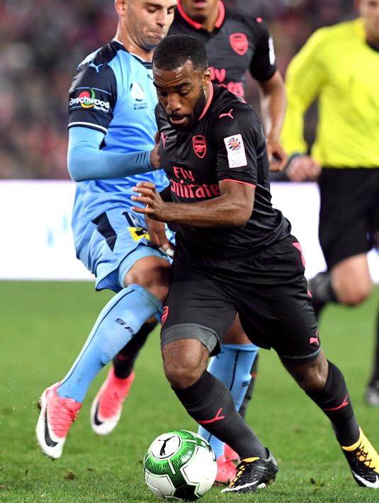 Alexandre Lacazette berusaha membawa bola dari kawalan pemain Sydney FC Christopher Zuvela pada pertandingan persahabatan di Sydney (13/7). Lacazette bermain sebagai pemain pengganti menggantikan Danny Welbeck di menit 68. (AFP Photo/William West)