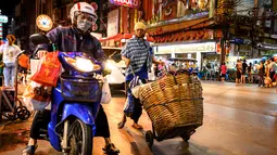 Seorang pengantar barang mendorong gerobaknya di sebuah jalan di Chinatown Bangkok (16/9/2020). Di Chinatown Bangkok terdapat juga beberapa kuil penting, salah satunya Wat Traimit yang ada di ujung jalan Yao Warat. (AFP/Mladen Antonov)